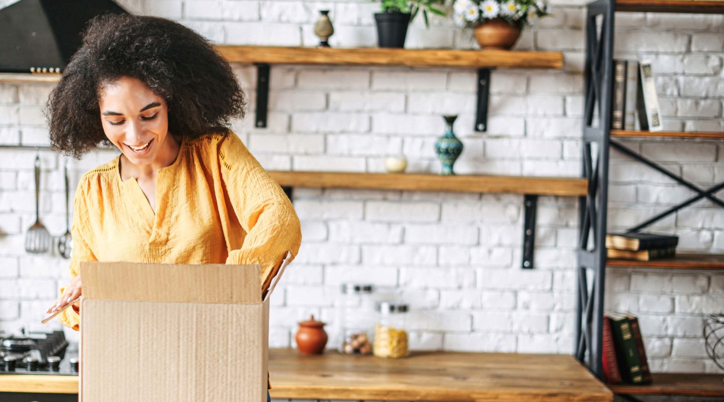 happy woman opening a package on her kitchen counter