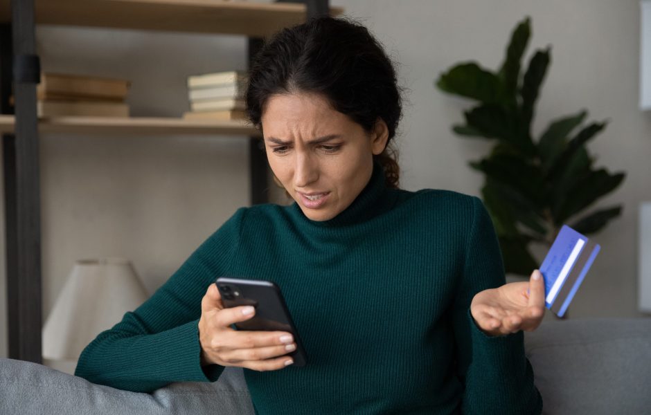 confused woman holding credit card and shopping on phone